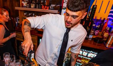 A bartender pouring drinks at the Swigg