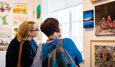 Two individuals viewing an exhibition in the Glynn Vivian Art Gallery