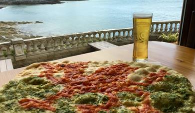 Pizza and a pint of beer with Mumbles lighthouse in the background.