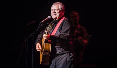Max Boyce on stage with guitar