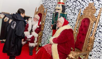Photo of a young girl meeting Father Christmas and Mrs Claus