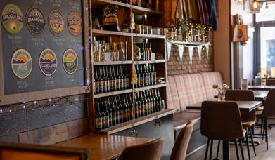 The Taproom Mumbles interior with tables and chairs, and a selection of bottled beer and merchandise available