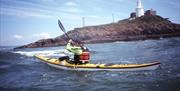 A boy kayaking around mumbles with Gower Adventures