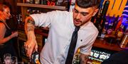 A bartender pouring drinks at the Swigg