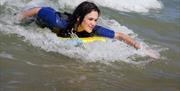A girl surfing with Gower Adventures
