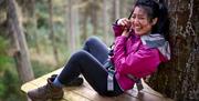 A lady in a pink jacket laughing whilst completing the Go Ape activities
