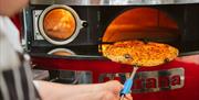 Lolis Mediterranean Restaurant chef taking pizza out of oven