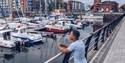A man looking out over boats in Swansea Marina.