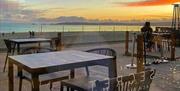 The Secret Beach Bar outdoor seating area with sunset over swansea bay