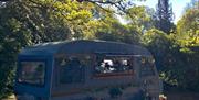 The Touring Tea Room positioned by some trees in the sunset