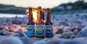 A bottle each of Gower Zero, Gower Oxwich and Gower Langland beers placed on the beach